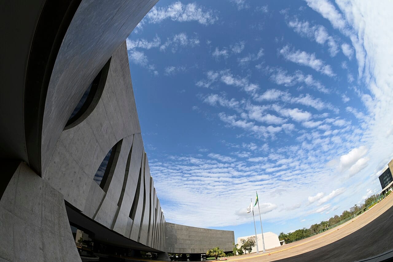 Fachada curva da sede do Superior Tribunal de Justiça, em Brasília, sob céu de nuvens